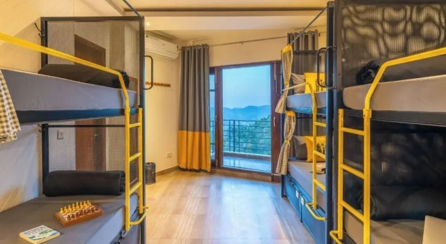 Кровать в общем номере с балконом и с красивым видом из окна The Hosteller Kasauli